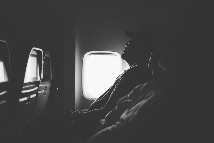 grayscale photo of three person sitting inside airplane